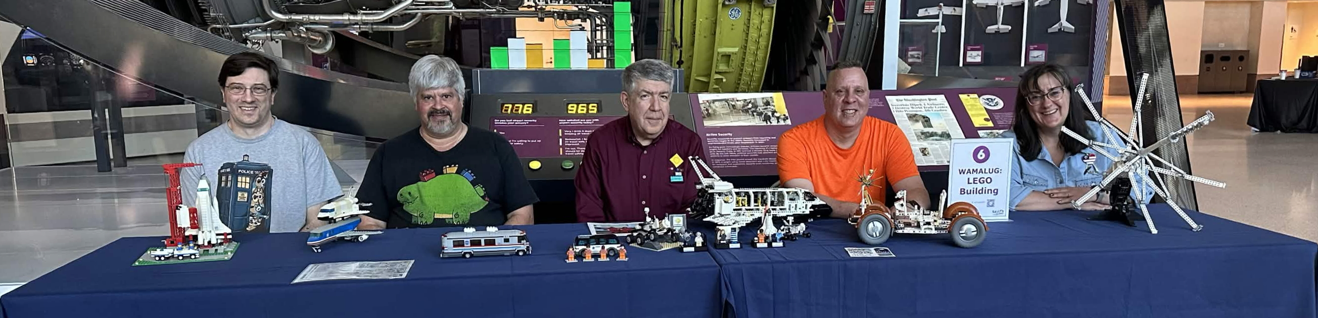 Five Wamalug participants and their creations among aircraft exhibits at a museum.